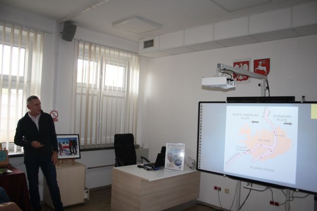 Jacek Podkościelny opowiada o podróży na Islandię. Na tablicy multimedialnej wyświetla się mapa Islandii.
