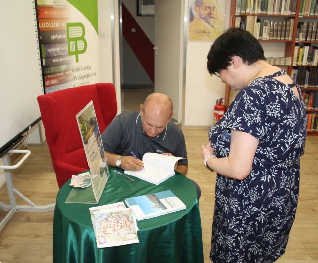 Janusz Malicki podpisuje swoje książki osobom, które je kupiły.