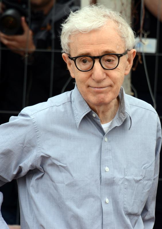 Zdjęcie wykonane w Cannes w 2016 roku. Woody Allen jest w charakterystycznych dla siebie okrągłych okularach. Ubrany jest w jednolitą koszulę z długim rękawem. Lekko się uśmiecha.