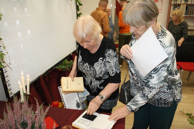 Uczestniczki Narodowego Czytania przybijają w książce pamiątkową pieczątkę.